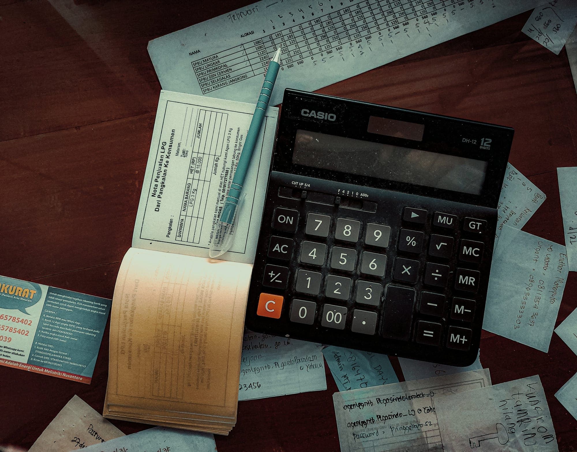 A calculator and paperwork on a wooden desk
