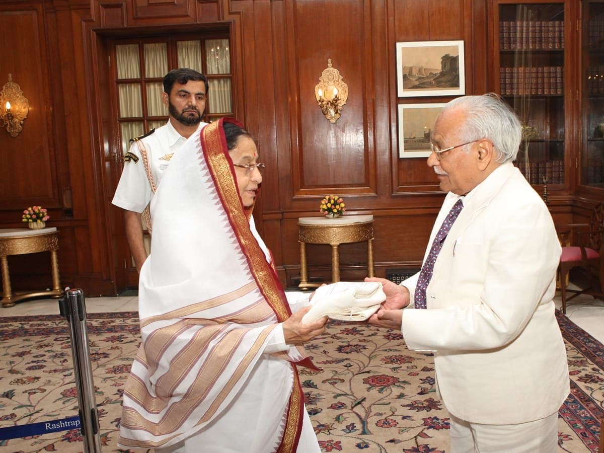 Shri Devraj Singh Surana, in a white suit, with the President of India in a wood-panelled room