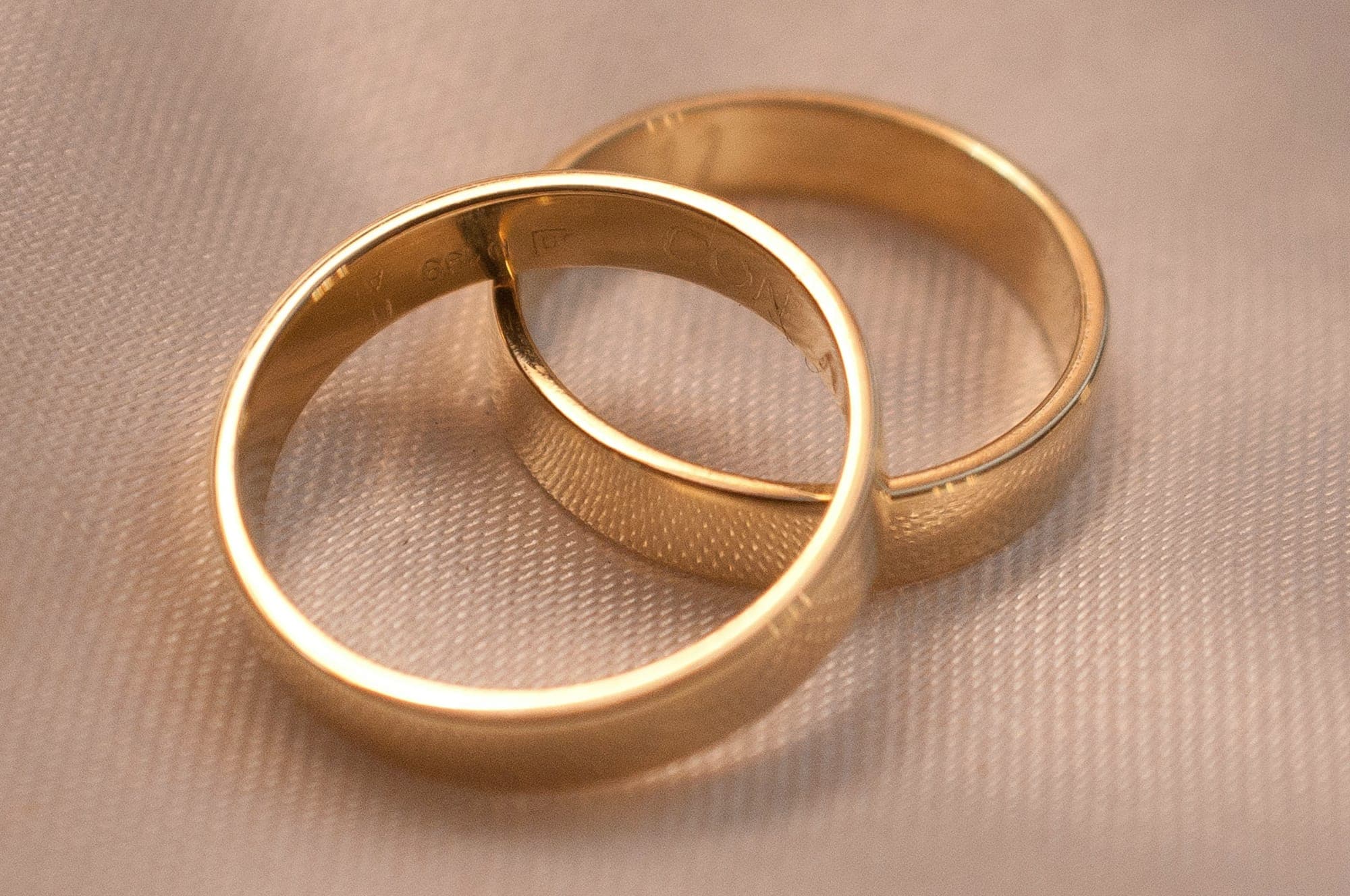 Two gold wedding rings on cream fabric