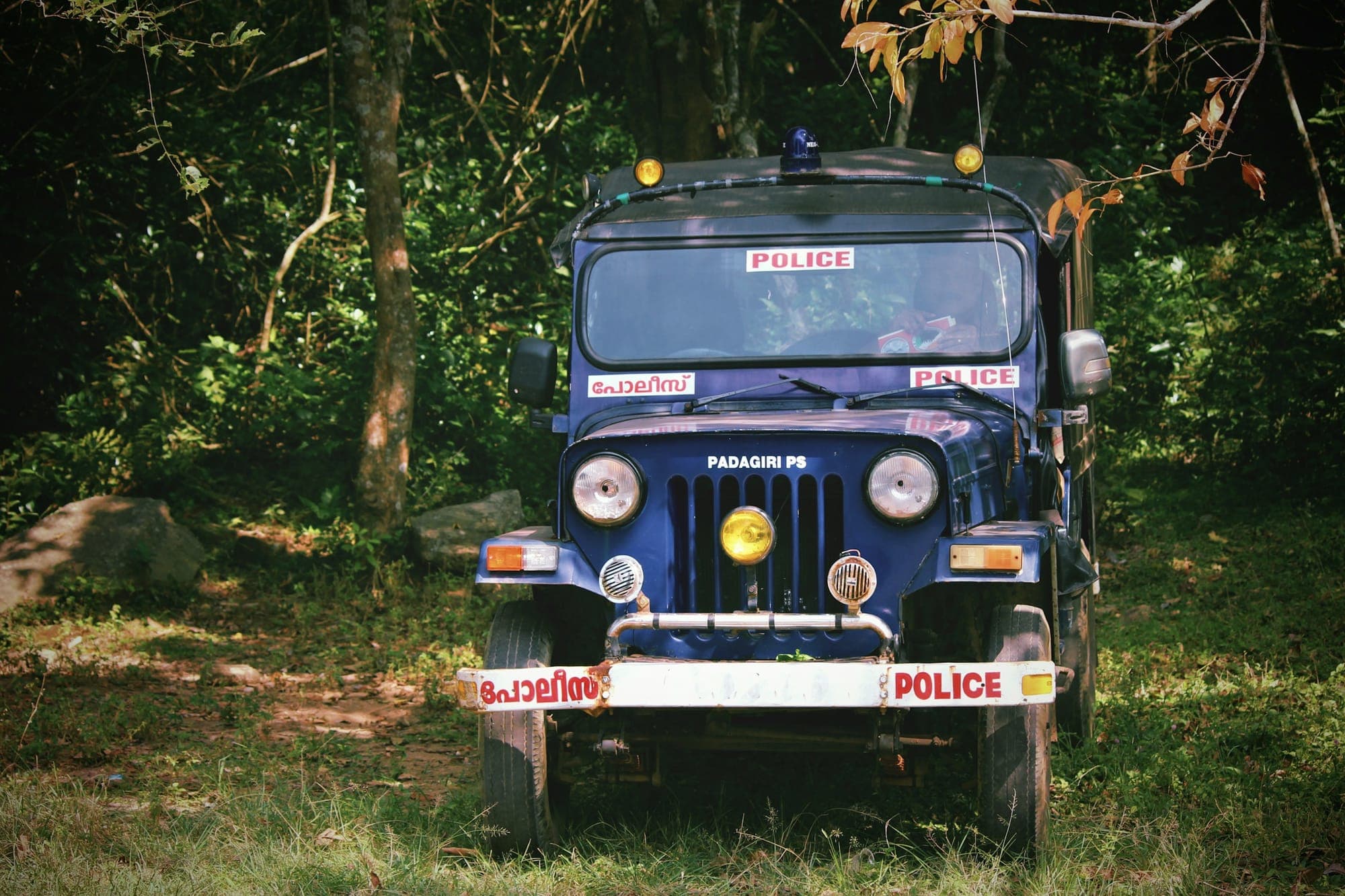 A Kerala Police jeep parked among trees