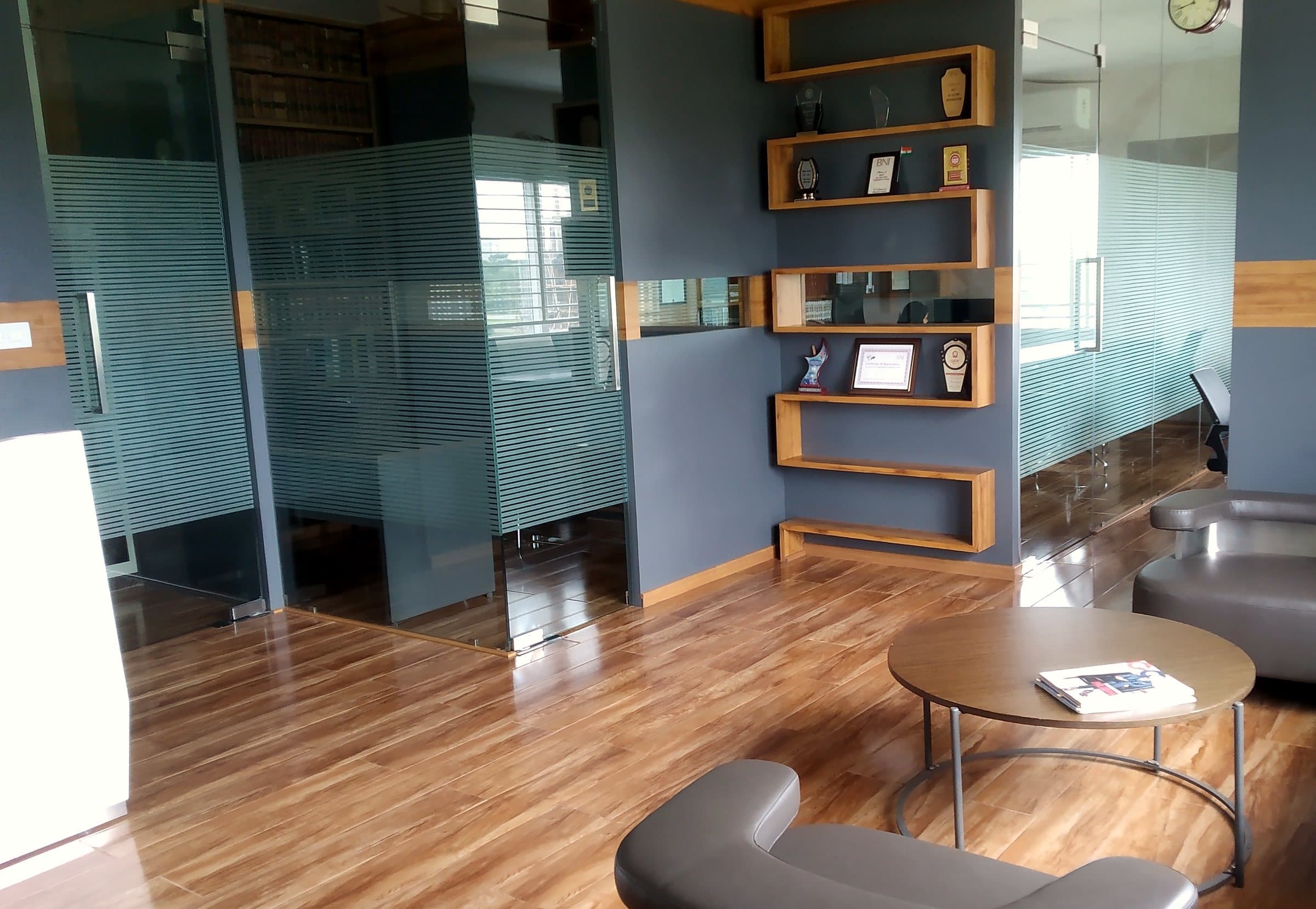 The firm's reception: leather armchairs around a round table, wooden shelves and frosted glass cabins